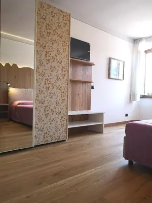 a room with two beds and a table and a picture at Ampia casa in Cavalese in Cavalese