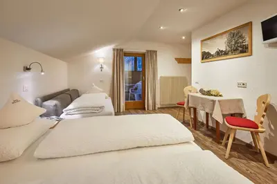 a hotel room with two beds and a table at Garni Irsara in San Cassiano