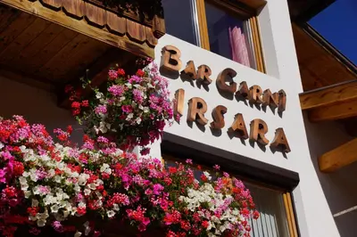 a sign for a bakery with flowers on a building at Garni Irsara in San Cassiano