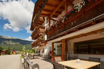 a patio with a table and chairs and a building at Garni Irsara in San Cassiano