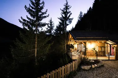 a house with a fence and trees in front of it at Mons Silva Private Luxury Chalets in Racines