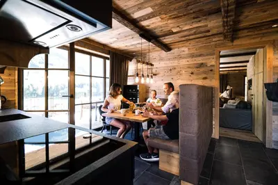 a group of people sitting at a table in a kitchen at Mons Silva Private Luxury Chalets in Racines