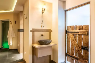 a bathroom with a sink and a wooden door at Hotel Monte44 in Selva di Val Gardena
