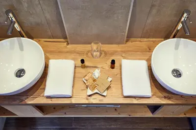 two sinks and towels on a wooden table in a bathroom at Hotel Tabladel in Colfosco