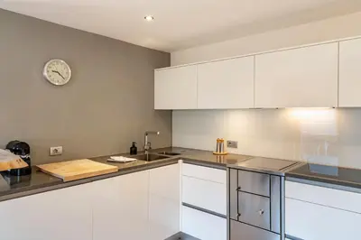 a kitchen with white cabinets and a clock on the wall at Ritschhof in Laion