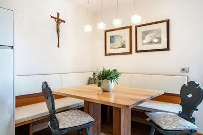 a dining room table with two chairs and a cross on the wall at Ritschhof in Laion