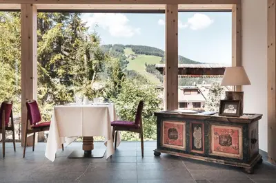 a table and chairs in a room with a large window at Hotel Chalet Corso in San Vigilio Di Marebbe