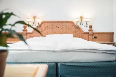 a bed with white sheets and pillows on it at Hotel Chalet Corso in San Vigilio Di Marebbe