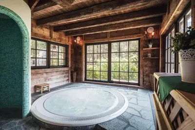 a large jacuzzi tub in a room with windows at Hotel Chalet Corso in San Vigilio Di Marebbe