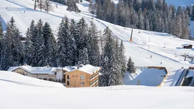 a building in the snow next to a ski slope at Hotel Seelaus in Alpe di Siusi