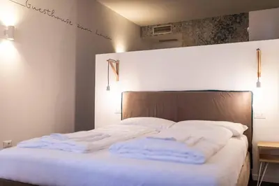 a bed with white sheets and pillows on it at Stay COOPER l Guesthouse zum Löwen in Merano