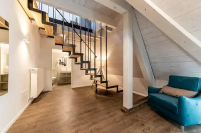 a living room with a blue couch and a staircase at Stay COOPER l Guesthouse zum Löwen in Merano