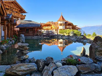 a reflection of a house in the water with rocks at Chalets Almdorf Haidenberg in Brunico