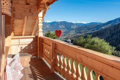 a balcony of a cabin with a view of the mountains at Chalets Almdorf Haidenberg in Brunico