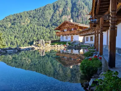 a reflection of a house in the water next to a mountain at Chalets Almdorf Haidenberg in Brunico