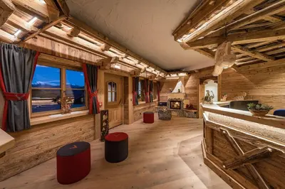 a large room with wooden walls and wooden floors and windows at Chalets Almdorf Haidenberg in Brunico