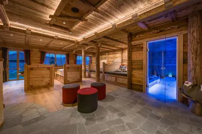 a large wooden room with a bed and stools at Chalets Almdorf Haidenberg in Brunico