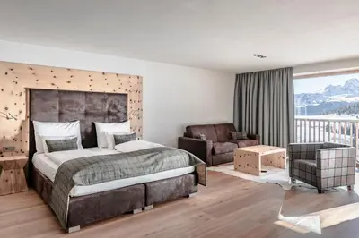 a bedroom with a bed and a couch and a chair at Sporthotel Sonne in Alpe di Siusi