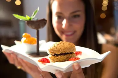 a woman holding a plate with a dessert on it at Sporthotel Sonne in Alpe di Siusi