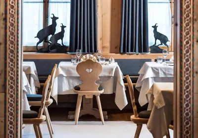 a reflection of a restaurant with tables with deer statues at Sporthotel Sonne in Alpe di Siusi