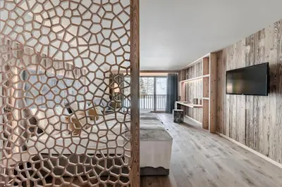 a living room with a large wooden wall with a tv at Sporthotel Sonne in Alpe di Siusi