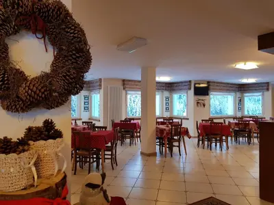 a dining room with red tables and chairs and windows at Santa Maria ad Nives in Canazei