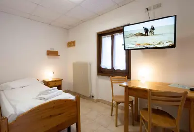 a room with a bed and a table and a tv at Santa Maria ad Nives in Canazei