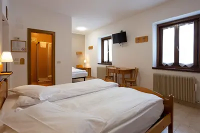 a bedroom with two white beds and a table at Santa Maria ad Nives in Canazei