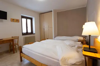 a bedroom with two beds and a desk and a window at Santa Maria ad Nives in Canazei