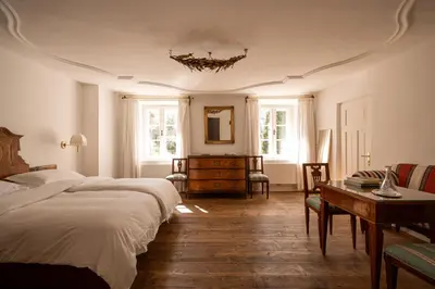 a bedroom with two beds and a table and windows at Ottmanngut Suite and Breakfast in Merano