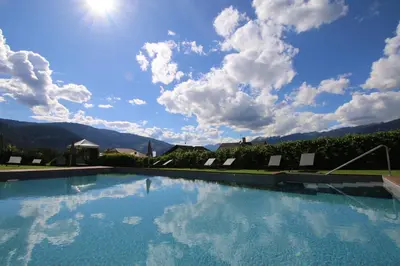 a large swimming pool with a blue sky with clouds at Hotel Lindnerhof in San Lorenzo di Sebato