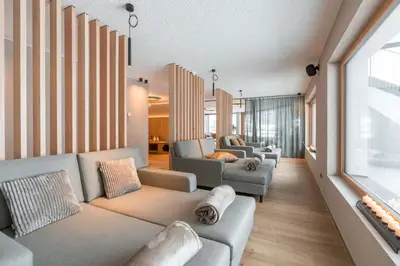 a living room with couches and a large window at Hotel Lindnerhof in San Lorenzo di Sebato