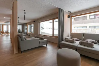 a living room with couches and a large window at Hotel Lindnerhof in San Lorenzo di Sebato