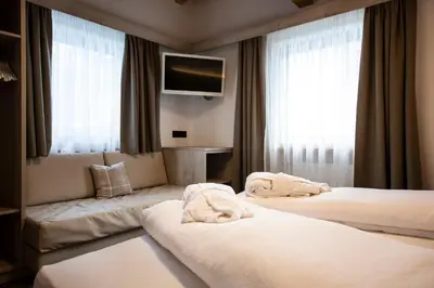a hotel room with two beds and a flat screen tv at Apartments & Garnì Pre Da Nai in La Villa
