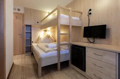 a small room with a bunk bed and a television at Apartments & Garnì Pre Da Nai in La Villa