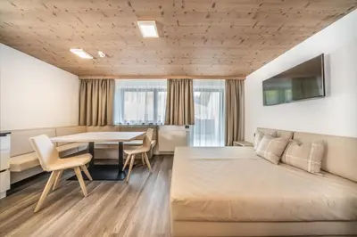 a hotel room with a bed and a table and chairs at Apartments & Garnì Pre Da Nai in La Villa