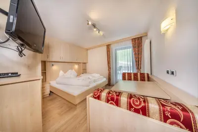 a room with two beds and a flat screen tv at Apartments & Garnì Pre Da Nai in La Villa