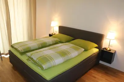 a bed with two green pillows and two lamps at Appartment Larcher - Manzoni in Merano