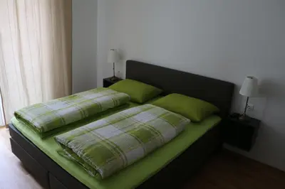 a bed with green pillows on it in a room at Appartment Larcher - Manzoni in Merano