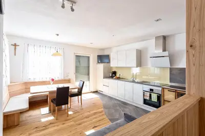 a kitchen with white cabinets and a table and chairs at Tschörlerhof in Barbiano