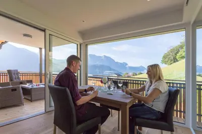 a man and woman sitting at a table on a balcony at Tschörlerhof in Barbiano
