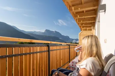 a woman sitting on a balcony with a glass of wine at Tschörlerhof in Barbiano