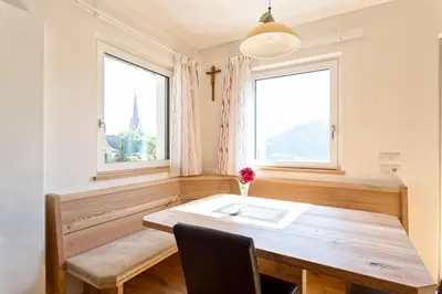 a dining room with a wooden table and two windows at Tschörlerhof in Barbiano
