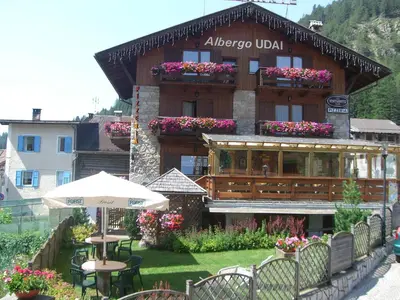 a building with an umbrella and tables and chairs at Garni Val Udai in Mazzin
