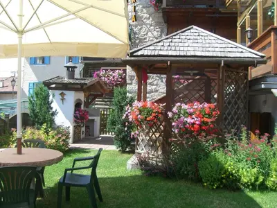 a garden with a gazebo with flowers and a table at Garni Val Udai in Mazzin