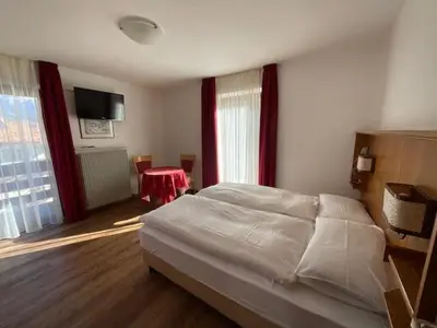a bedroom with a large bed and a red table at Garni Val Udai in Mazzin
