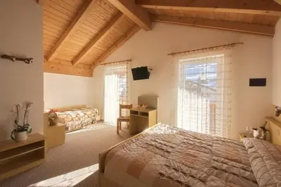 a bedroom with two beds and a large window at Hotel Vallechiara in Moena