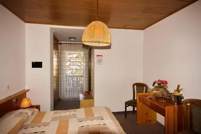 a bedroom with a bed and a desk and a table at Hotel Vallechiara in Moena