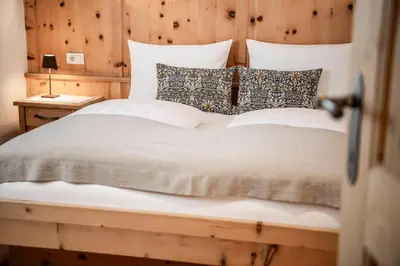 a bedroom with a white bed with a wooden wall at Christlrumerhof in Brunico
