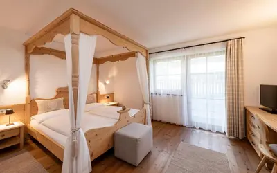 a bedroom with a canopy bed and a television at Christlrumerhof in Brunico